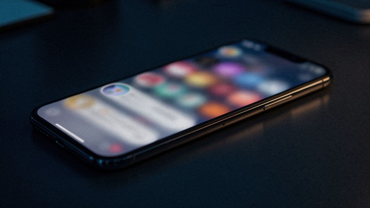 Karanlık masada ekranı parlayan akıllı telefon